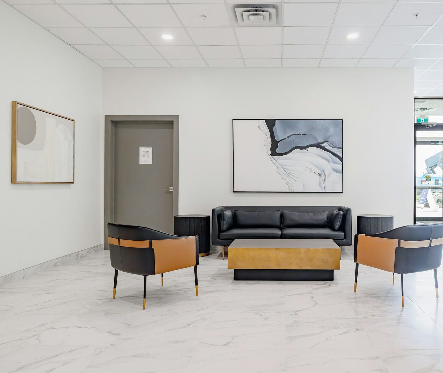 A bright reception lounge with a black sofa, two armchairs and a coffee table