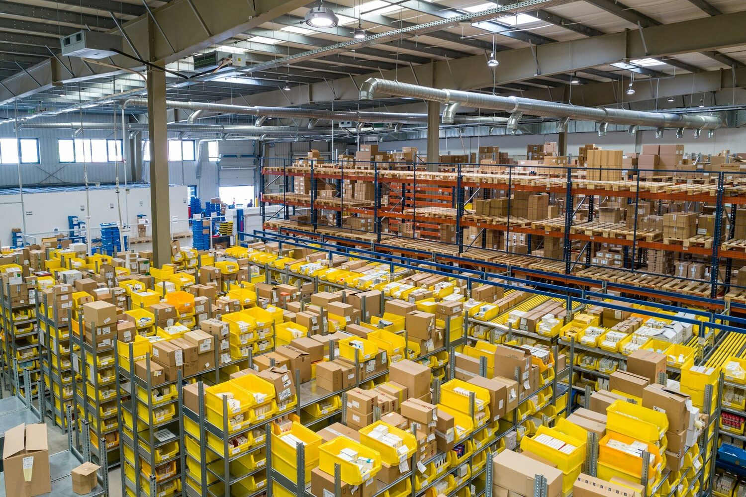 A warehouse with shelving, cartons and yellow bins